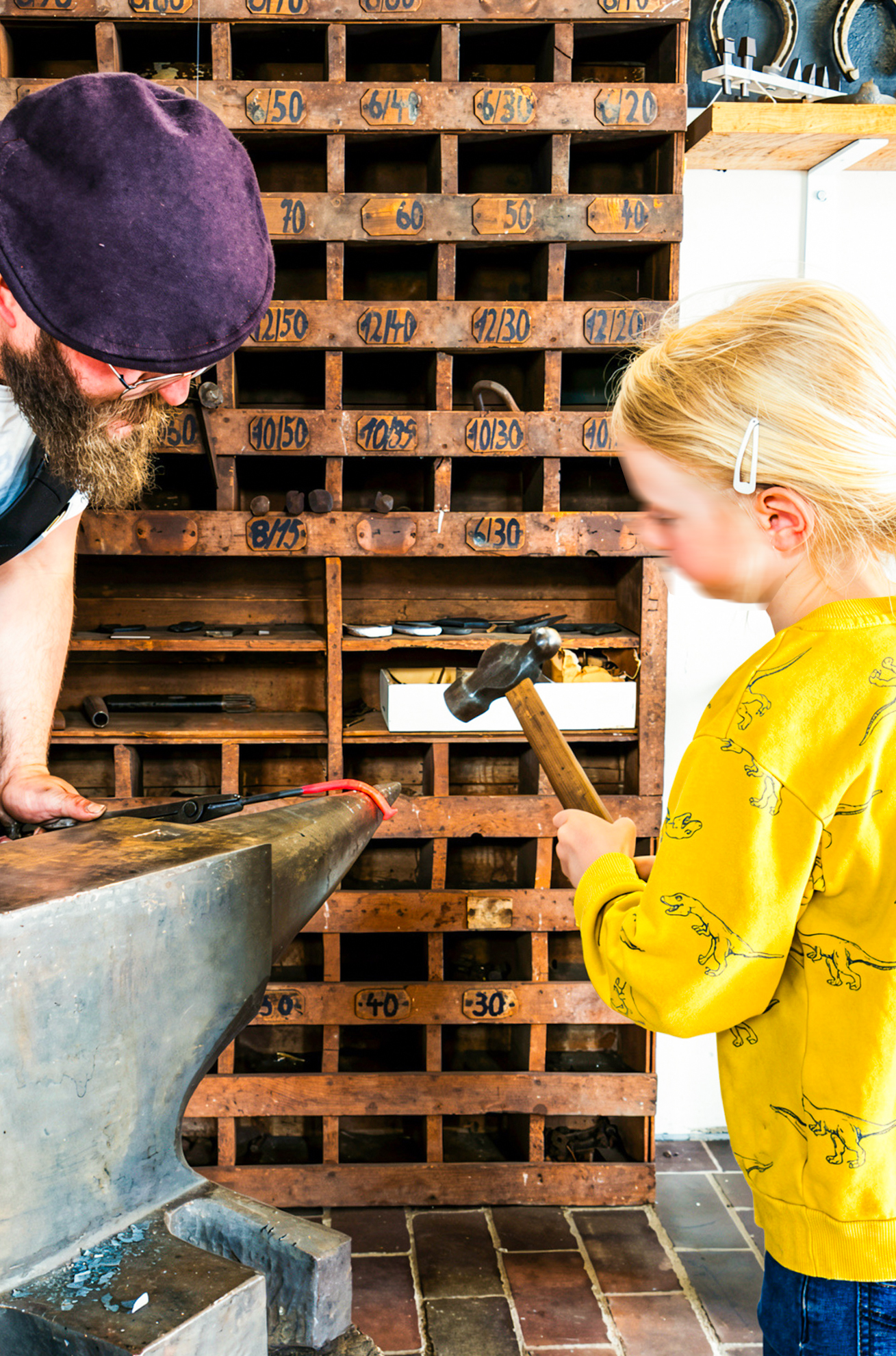 Sönke showing a child how to blacksmith at the anvil