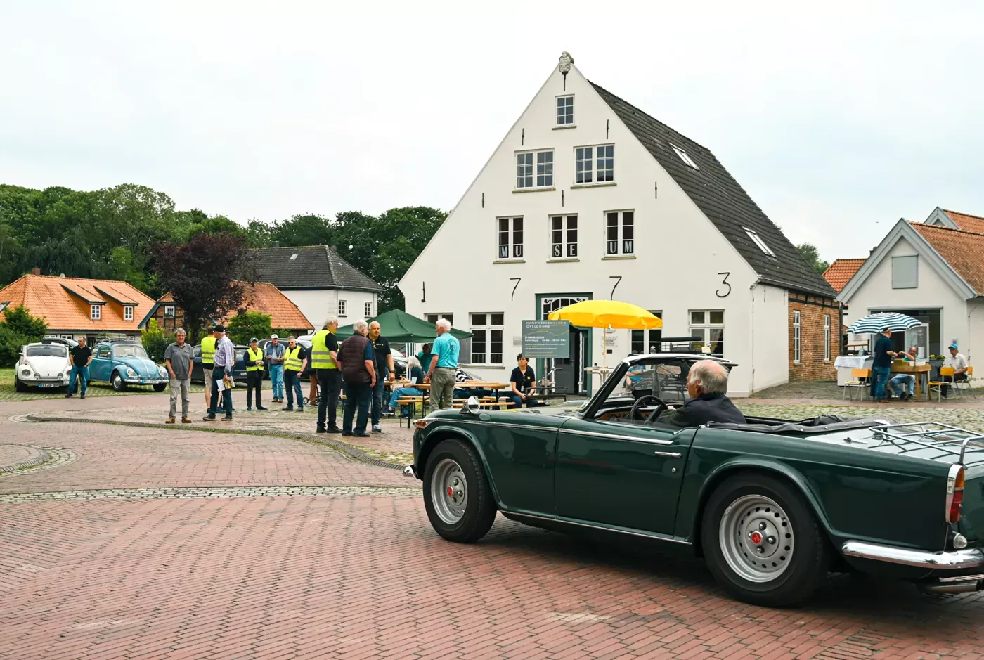 Das Museum an der Breiten Straße, ein weißes Giebelhaus, davor ein grüner Oldtimer und Gäste