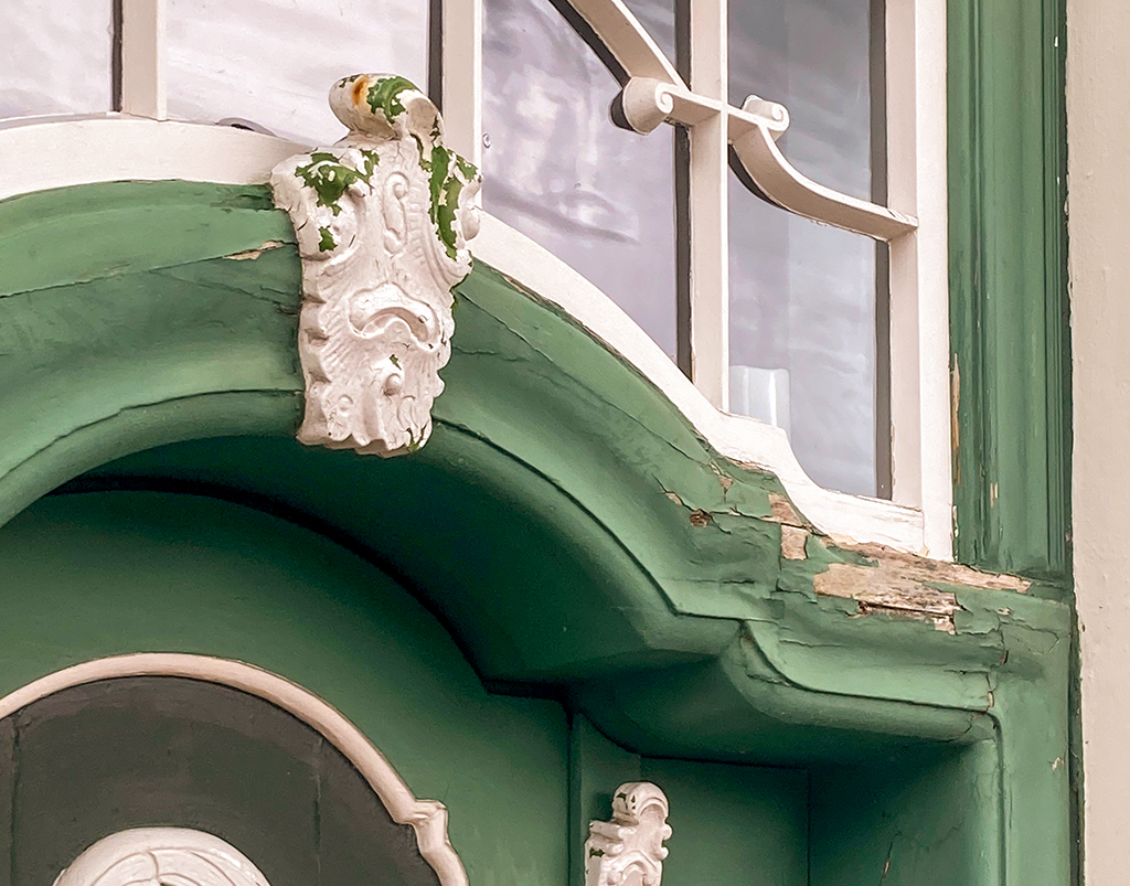 The Rococo door before restoration, showing flaking paint and visible damage